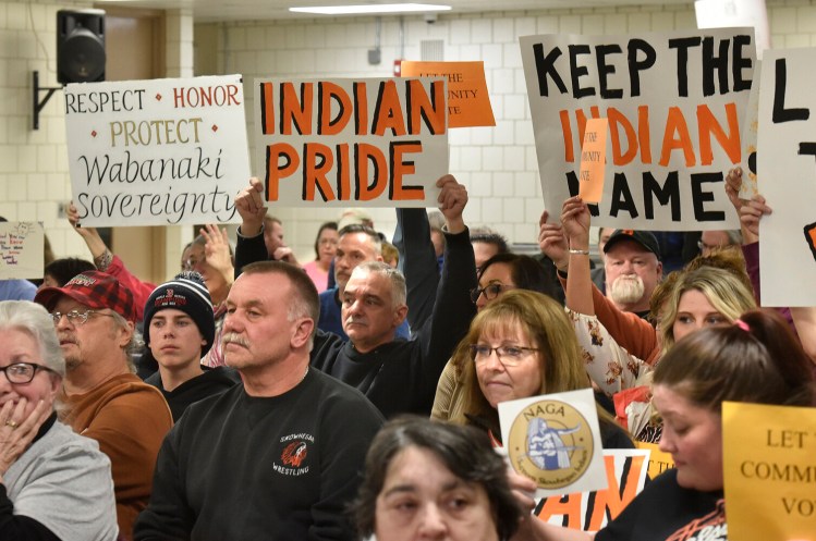 People for and against the use of the word Indian in School Administrative District 54 schools hold signs toward board members during a March 7, 2019, meeting in Skowhegan.