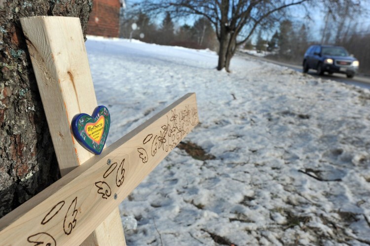A homemade cross with three sets of angel wings and a personal message rests against a tree Wednesday, marking the location where three youths were killed Sunday morning in a car accident on the Hinckley Road in Clinton.