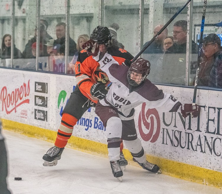 Edward Little's Campbell Cassidy and Biddeford/Massabesic/Old Orchard Beach's Brayden Locke scuffle near the board during Tuesday's Class A boys hockey preliminary playoff game in Auburn.