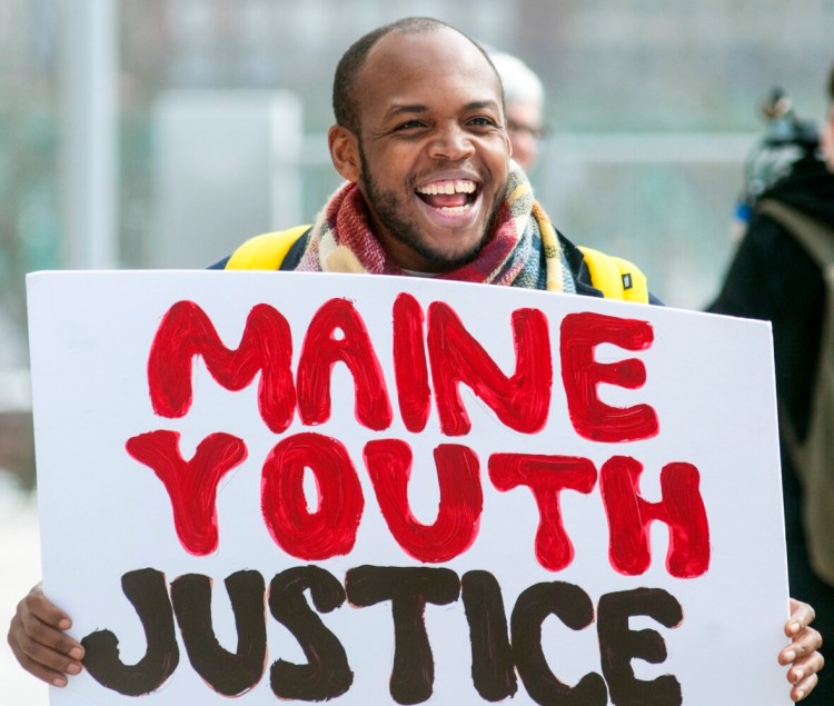 Darryl Shepherd Jr. of Biddeford carries a sign as he leads call-and-response cheers during Maine Youth Justice's event Tuesday in Augusta. Youth activists are demanding that the state immediately shut down the Long Creek Youth Development Center.