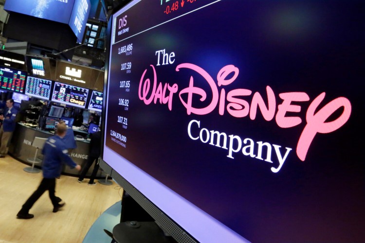 FILE - In this Aug. 8, 2017, file photo, The Walt Disney Co. logo appears on a screen above the floor of the New York Stock Exchange. The Walt Disney Co. said Tuesday, Feb. 4, 2020, that profit fell 23% in its latest quarter to $2.13 billion as it absorbed losses, and a big revenue boost, from its new streaming service, Disney Plus. (AP Photo/Richard Drew, File)