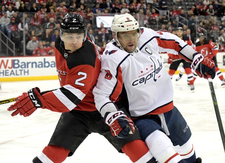 Washington left wing Alex Ovechkin, right, battles New Jersey defenseman Colton White during Saturday's game  in Newark, N.J. Ovechkin's goal in the third period to made the score 2-2 and was the 700th of his career.
