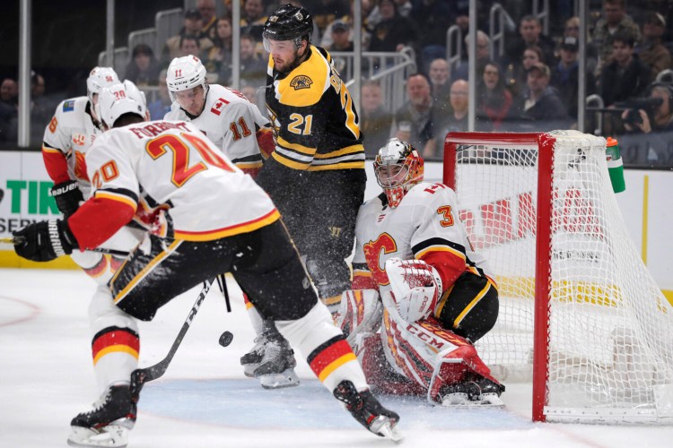New Boston left wing Nick Ritchie, center, tries to tip the puck past Calgary goaltender David Rittich during his first game with the Bruins on Tuesday after being traded Monday.

