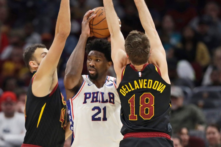 Philadelphia's Joel Embiid, center, squeezes between Cleveland's Ante Zizic, left, and Matthew Dellavedova during Wednesday's game in Cleveland. 