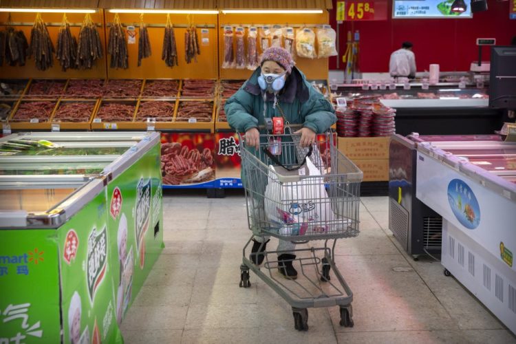 A woman shops at a grocery store in Beijing on Saturday. One Chinese city has banned almost all residents from leaving their homes, allowing only one person from each household out to shop for food once every two days.