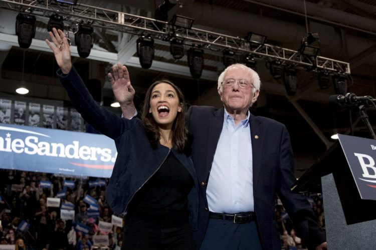 Democratic presidential candidate Bernie Sanders, accompanied by Rep. Alexandria Ocasio-Cortez, D-N.Y., takes the stage at a campaign stop at the University of New Hampshire on Monday, a day before the state's primary election.