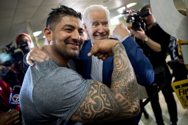 Democratic presidential candidate Joe Biden flexes his arm along with Jaime Karnilaw of Concord, N.H., as they pose for a photograph Monday at a campaign stop in Gilford, N.H. Biden sought to lower expectations for his performance in Tuesday's primary.