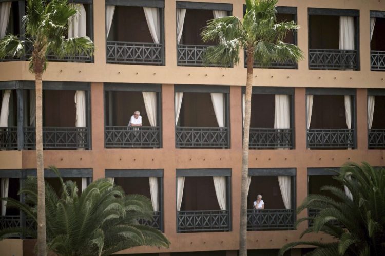 People stand at their balconies at the H10 Costa Adeje Palace hotel in Tenerife, Canary Island, Spain, on Tuesday. Spanish officials say a tourist hotel on the Canary Islands has been placed in quarantine after an Italian doctor staying there tested positive for the new coronavirus. 