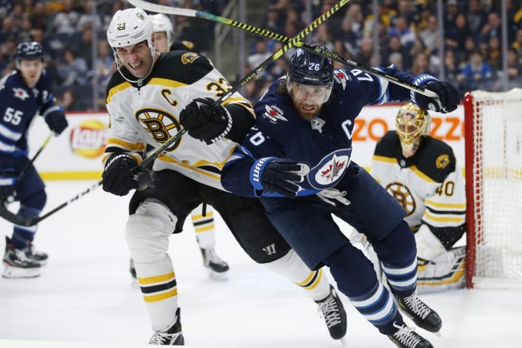 Winnipeg Jets' Blake Wheeler (26) and Boston Bruins' Zdeno Chara (33) chase the puck as goaltender Tuukka Rask (40) watches during the second period of a January 2020 game in Winnipeg, Manitoba. 