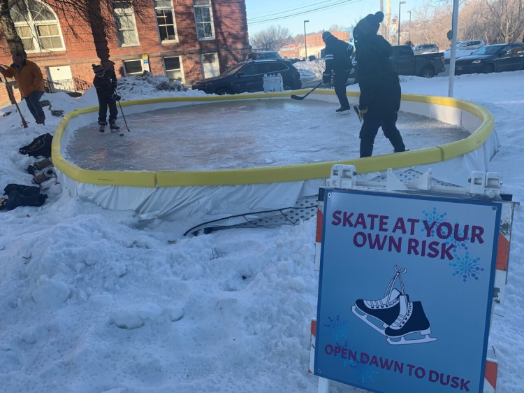 Cutting some time on the ice on a frigid Friday afternoon are, from left, Eddie Goff, 11, of Norridgewock, John Robertson, 46, of Waterville, and Noah Robinson, 11, of Waterville. Bert Languet, "The Iceman" off the rink to the left, donated the rink to the Children's Discovery Museum and helped set it up.