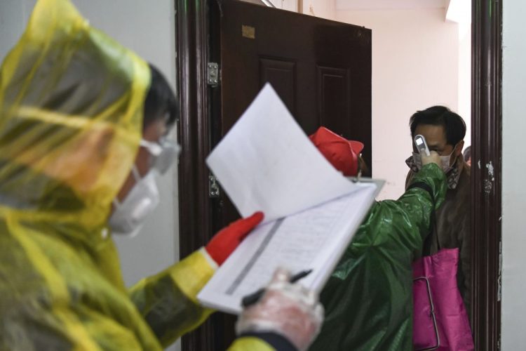 Workers go door-to-door to check the temperatures of residents during a health screening campaign in the Qingheju Community, Qingshan District of Wuhan in central China's Hubei Province, on Tuesday. 