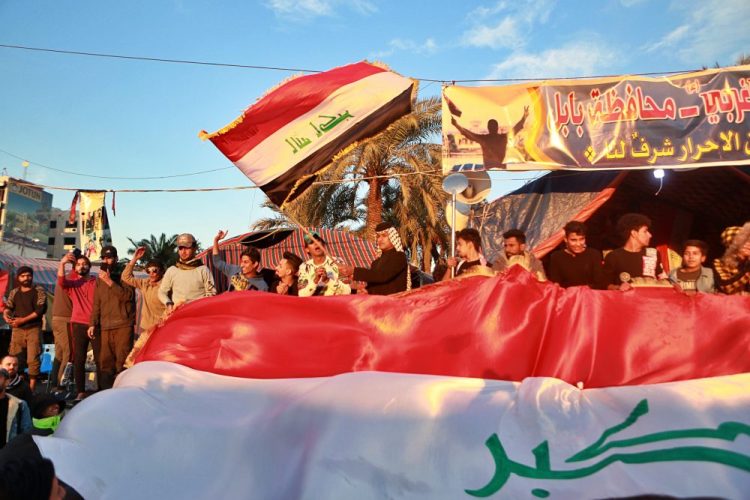 Anti-government protesters chant slogans while holding  national flags during a demonstration against the newly appointed Prime Minister Mohammed Allawi in Tahrir Square, Baghdad, Iraq, on Monday.