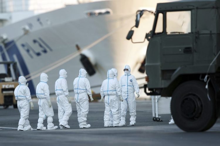 Officials with protective suits prepare to work around the quarantined cruise ship Diamond Princess in the Yokohama port on Monday in Yokohama, Japan. Japan’s health ministry said Monday that dozens of people on the quarantined cruise ship have tested positive for a new coronavirus virus. 