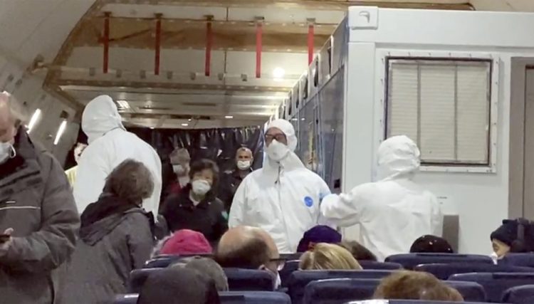 U.S. passengers who evacuated off the quarantined cruise ship the Diamond Princess and officials wait for the takeoff of a Kalitta Air airplane bound for the U.S., at Haneda airport in Tokyo.