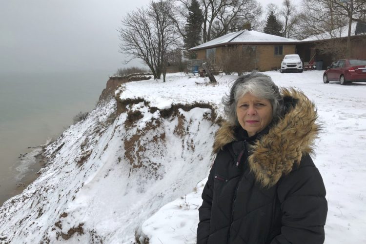 Rita Alton stands next to her house on the edge of a cliff overlooking Lake Michigan near Manistee, Mich., last month. When her father built the 1,000-square-foot brick bungalow in the early 1950s, more than acre of land lay between it and the drop-off overlooking the water. 