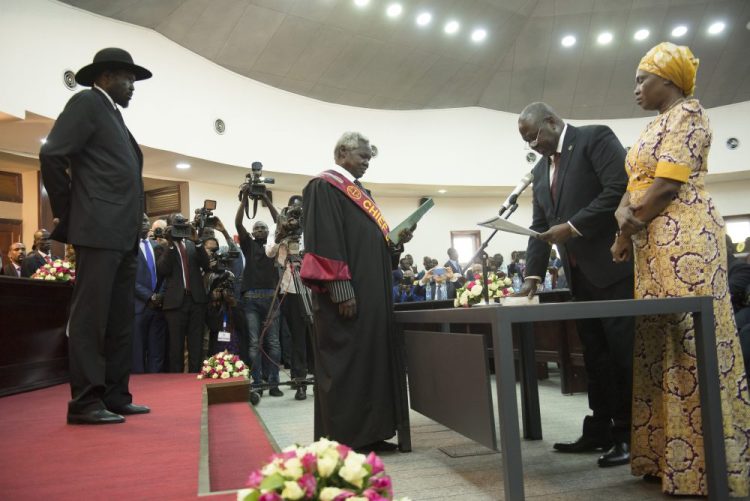The president of South Sudan, Salva Kiir, left, swears in Riek Machar as the first vice president of South Sudan on Saturday. South Sudan opened a new chapter in its fragile emergence from civil war Saturday as rival leaders formed a coalition government. 