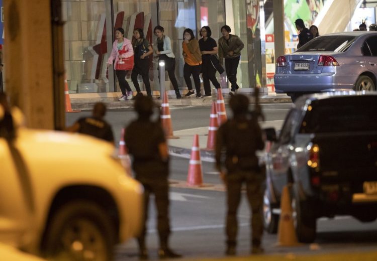 People who were able to get out of Terminal 21 Korat mall walk outside the building in Nakhon Ratchasima, Thailand on Sunday. A soldier who holed up in a popular shopping mall in northeastern Thailand shot multiple people on Saturday, killing at least 20 and injuring 31 others, officials said.