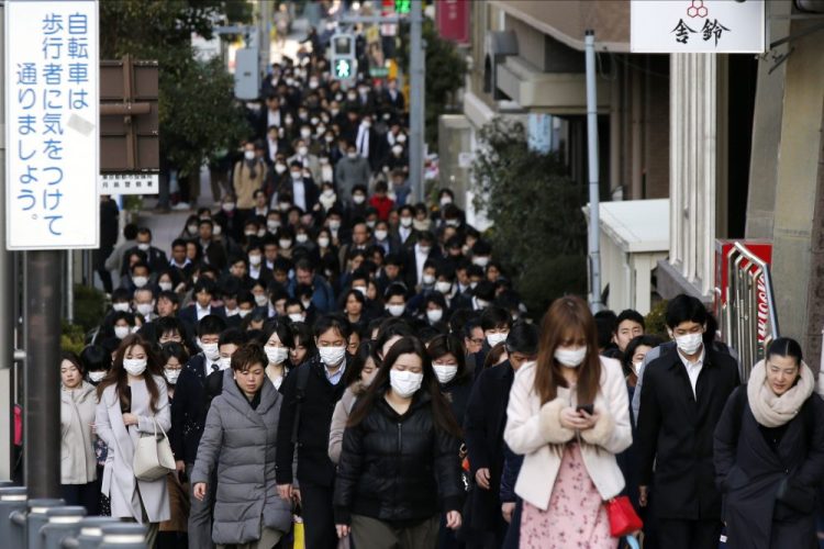 People wear masks  during morning rush hour on Feb. 20 in Tokyo. Prime Minister Shinzo Abe has called on companies to allow employees to work from home. Sri Lanka and Laos imposed price caps for face masks, while India restricted the export of personal protective equipment.