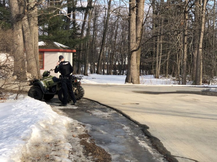 A Skowhegan police officer makes a telephone call Sunday from Robinson Street, where an ATV crash injured at least one man.