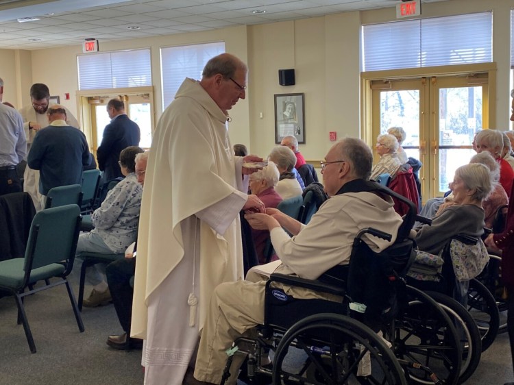 Bishop Robert P. Deeley gives communion Wednesday to a resident of the Mount Saint Joseph Retirement Home in Waterville.