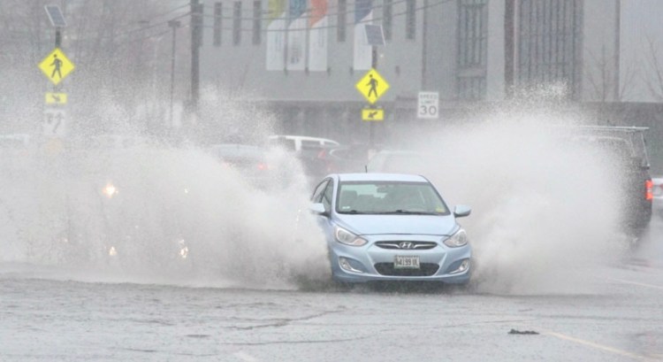 A car drives through standing water on Commercial Street in Portland on Thursday morning.
