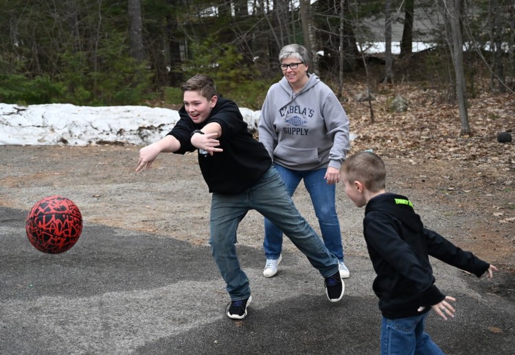 Barb Childs of Waterboro looks on as Wyatt 13, passes the basketball during a game at Childs' home. To the right is Gavin, 6.  
