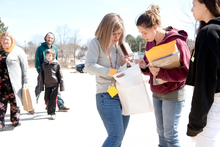 Emily Braga, center, shows Catherine Hughes the learning materials inside the learning packet Hughes picked up for her children at Fairview Elementary School in Auburn on Wednesday. Public elementary schools throughout Auburn handed out the packets to each student so they have materials to work on during school shutdowns due to the coronavirus. "This is amazing. I was nervous about the school thing," said Hughes, the mother of two Fairview students and one high school freshman, Kiara Richards, right. "Now we can be somewhat normal and the kids' schedule won't change as much," Hughes said. Auburn Mayor Jason Levesque stopped at Fairview on Wednesday. "I plan to hit two schools a day to help when I can," he said. "But the teachers got this down and have taken care of it all. My big thing is to find any holes that I can help with, but things are going amazingly well," he said.