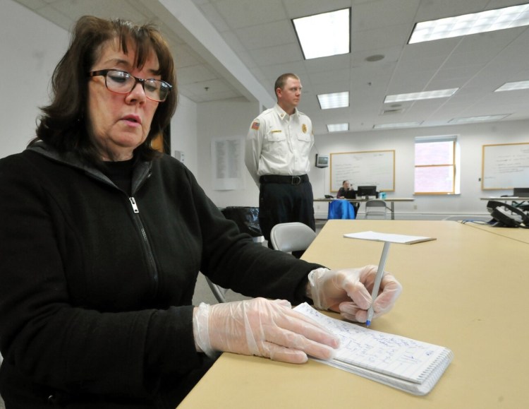 Waterville Morning Sentinel reporter Amy Calder wears protective gloves Monday as she reports on the coronavirus pandemic at the new Emergency Operations Center at the Waterville Fire Department. Calder was screened with another journalist before being allowed access to the building. 
