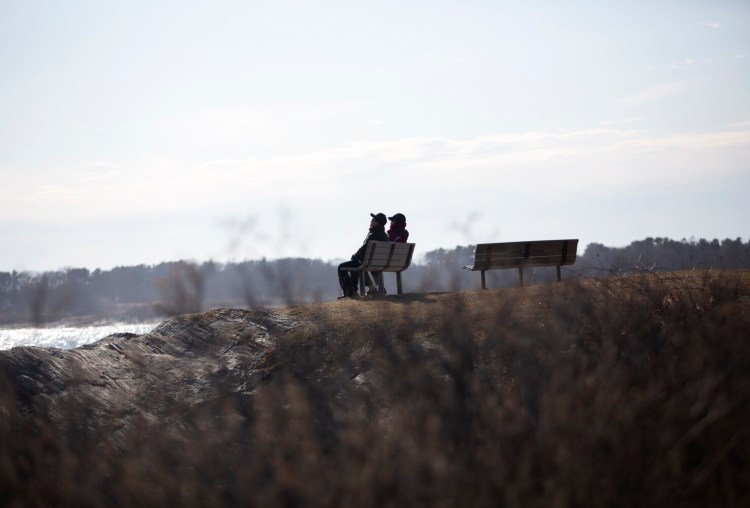 A couple sit on a bench at Kettle Cove State Park on Thursday, March 26, 2020. 
