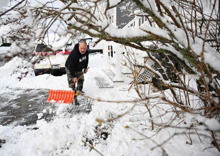 Esi Mohbiti of Maple Street in Saco shovels off his walkway after the overnight snowfall. 