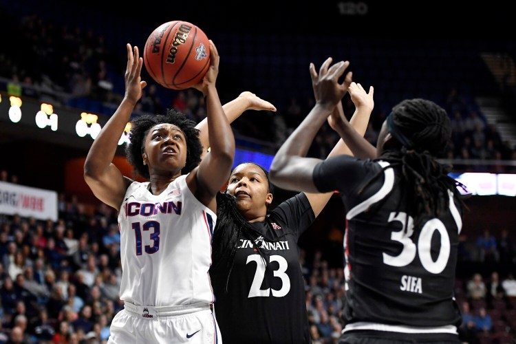 Connecticut’s Christyn Williams shoots over Cincinnati’s IImar’I Thomas, center, and Florence Sifa during the Huskies’ 87-53 win in the American Athletic Conference final on Monday.