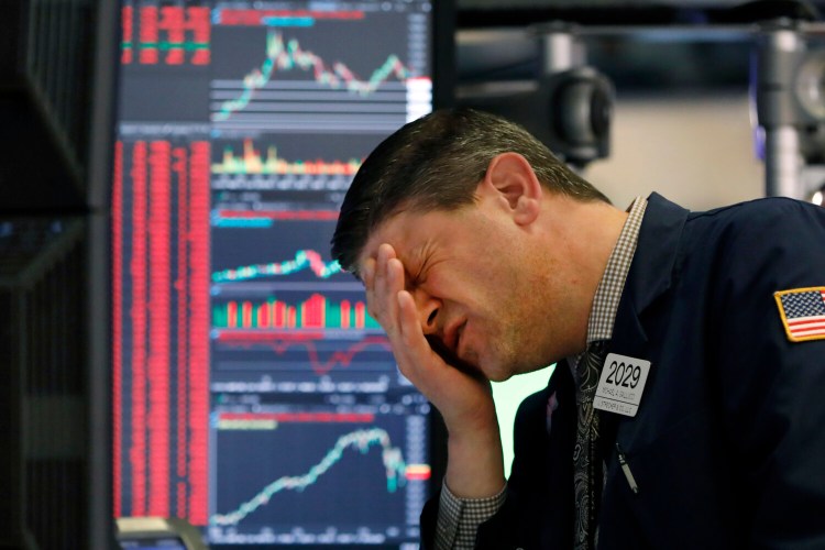 Trader Michael Gallucci works at his post on the floor of the New York Stock Exchange on Wednesday. The Dow industrials closed down 1,465 points, or 5.9%, as investors wait for a more aggressive response from the U.S. government to economic fallout from the coronavirus. 