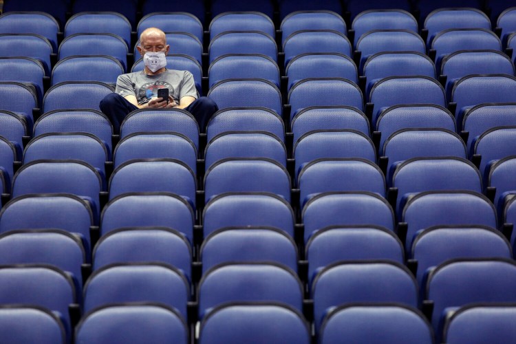 Mike Lemcke, from Richmond, Va., sits in an empty Greensboro Coliseum after the the Atlantic Coast Conference tournament in Greensboro, N.C. was canceled on Thursday. Sports could be on hold much longer than expected after the CDC recommended that in-person events of 50 or more people be called off for the next eight weeks. 