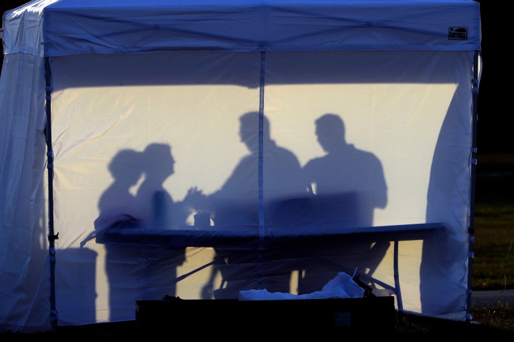 Medical personnel are silhouetted against the back of a tent before the start of coronavirus testing in the parking lot outside of Raymond James Stadium early Wednesday in Tampa. 