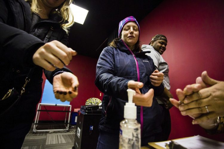 Sharon Trask and other voters use hand sanitizer as they stand in line to vote at Lincoln Lodge Polling station in Chicago's 1st ward on Tuesday. Election officials promoted voting early and casting ballots by mail in an attempt to control crowds and curb the spread of coronavirus. 