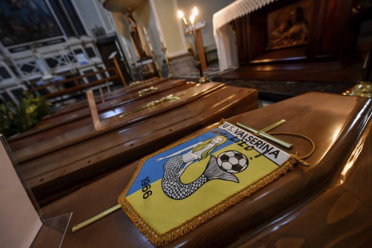 Coffins, one of them with the pennant of the local soccer team, wait in a church to be transported to a cemetery in Serina,  Northern Italy, on Saturday. Claudio Furlan/LaPresse via AP