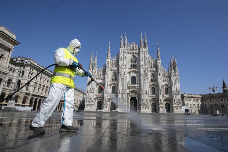 A worker sprays disinfectant to sanitize Duomo square, as the city's main landmark, the Gothic cathedral, stands out in background, in Milan, Italy, on Tuesday.