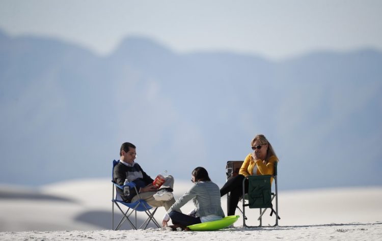 Visitors relax March 5, on a gypsum dune in White Sands National Park at Holloman Air Force Base, N.M.