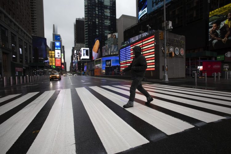 A man crosses the street in a nearly empty Times Square, which is usually very crowded on a weekday morning, on Monday in New York. Gov. Andrew Cuomo has ordered most New Yorkers to stay home from work to slow the coronavirus pandemic. 