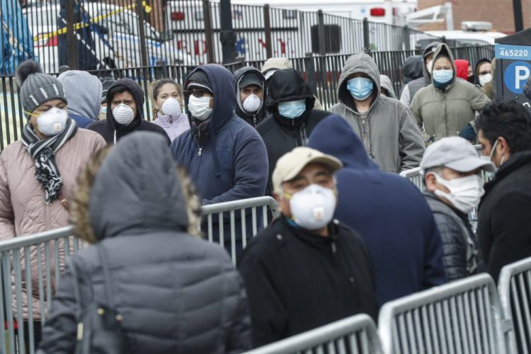 Patients wear personal protective equipment while maintaining social distancing as they wait in line for a COVID-19 test at Elmhurst Hospital Center on Wednesday in New York.