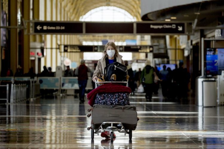 A woman wearing a mask walks through a terminal at Ronald Reagan Washington National Airport on Monday in Arlington, Va. 