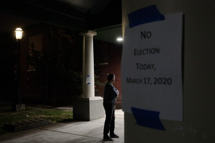 A man, who hoped to vote in the scheduled primary election Tuesday, stands outside a closed polling station at Schiller Recreation Center in Columbus, Ohio. U.S. elections have been upended by the coronavirus pandemic. At least 13 states have postponed voting and more delays are possible as health officials warn that social distancing and other measures to contain the virus might be in place for weeks, if not months.
