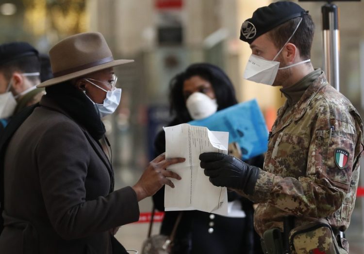 Italian police officers and soldiers check passengers leaving from Milan's main train station on Monday.
