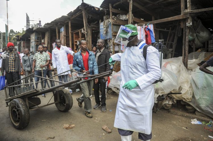 A Kenyan Health Ministry official sprays disinfectant onto a hand-cart to control the spread of the coronavirus in a outdoor street market in Nairobi. John Muchucha/Associated Press