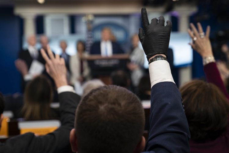 Reporters raise their hands to ask President Trump questions during a press briefing March 16 with the coronavirus task force, at the White House in Washington.