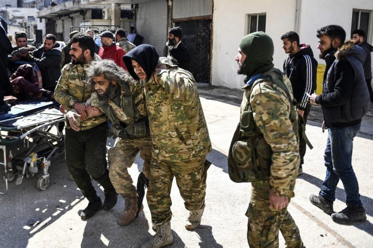 Turkey-backed opposition fighters help a man wounded in fighting with Syrian government forces and their allies in Sarmin, Syria, on Sunday. Fighting on the ground in Idlib continued Tuesday as Turkey shot down a Syrian warplane  – the third time since Sunday.