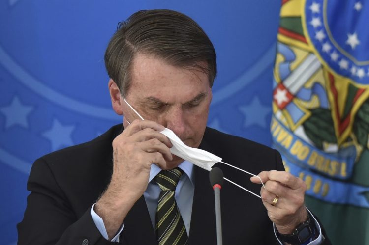 Brazil's President Jair Bolsonaro puts on a mask during a press conference on the coronavirus at the Planalto Presidential Palace in Brasilia, Brazil, on March 18.