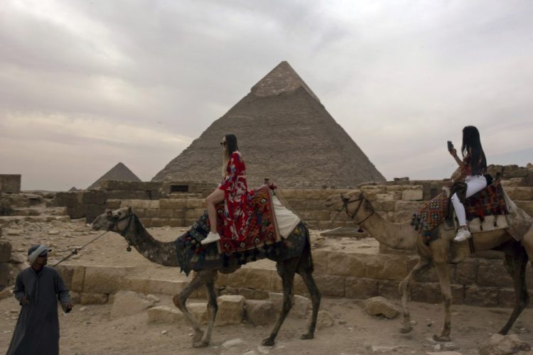 Two tourists ride camels at the Giza Pyramids near Cairo on March 10. The country's prime minister announced on Tuesday a two-week, 7 p.m. to 6 a.m. curfew for its over 100 million people to slow the spread of the new coronavirus. 