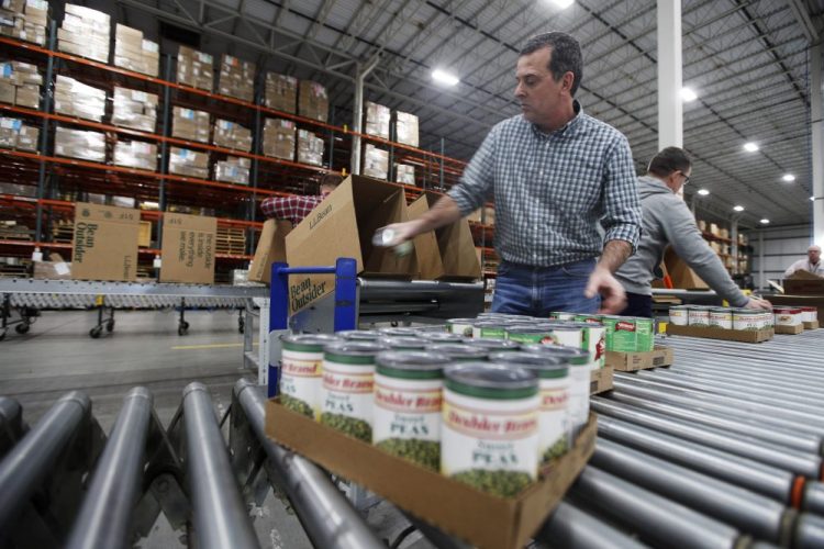 Mike Goodhartt and other workers at the L.L. Bean shipping center in Freeport box up donated foods Tuesday to be distributed to food pantries across the state. The outdoors retailer, which is experiencing sinking sales because of coronavirus, is partnering with the Good Shepherd food bank.