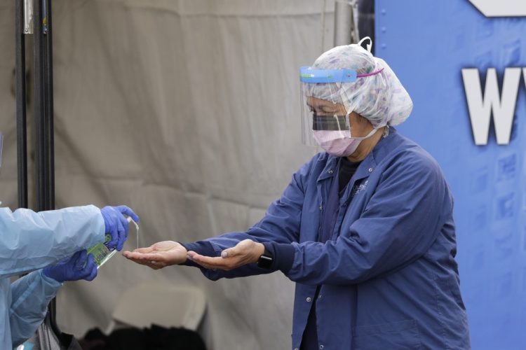 Theresa Malijan, a registered nurse, gets hand sanitizer after taking a nasopharyngeal swab from a patient at a drive-through COVID-19 testing station for University of Washington Medicine patients in Seattle on March 17. The United States has a critical shortage of protective equipment needed to keep health care workers safe from the coronavirus. 